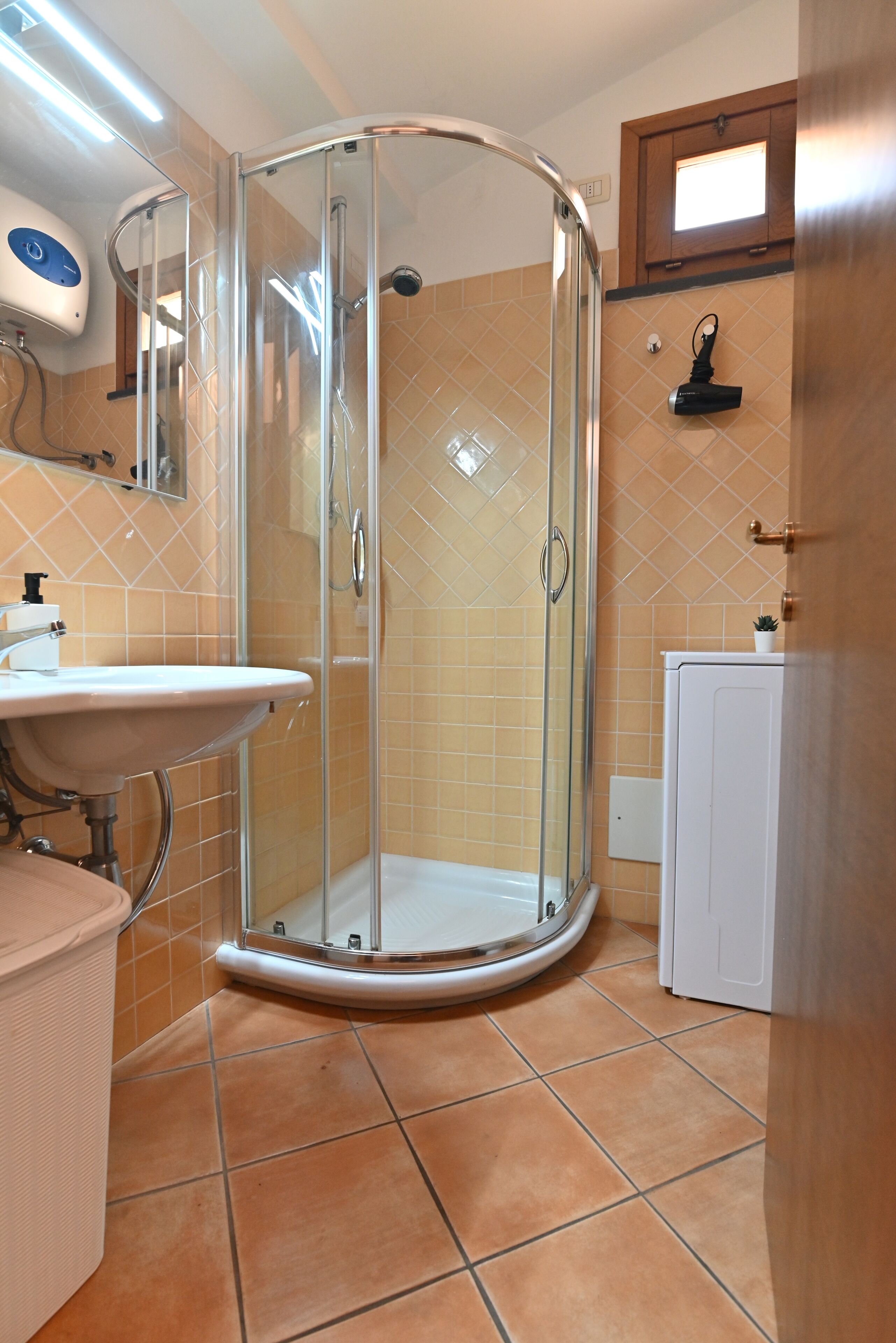 A bathroom with a glass-enclosed shower, a sink, and a cabinet.