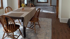 A dining area with a large table, wooden chairs, a rug, and a ceiling light fixture. - Delightful 2-bedroom fully remodeled house with AC in charming Oshkosh (Oshkosh)