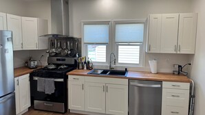 A modern kitchen with white cabinets, stainless steel appliances, a gas stove, and a dishwasher. - Delightful 2-bedroom fully remodeled house with AC in charming Oshkosh (Oshkosh)