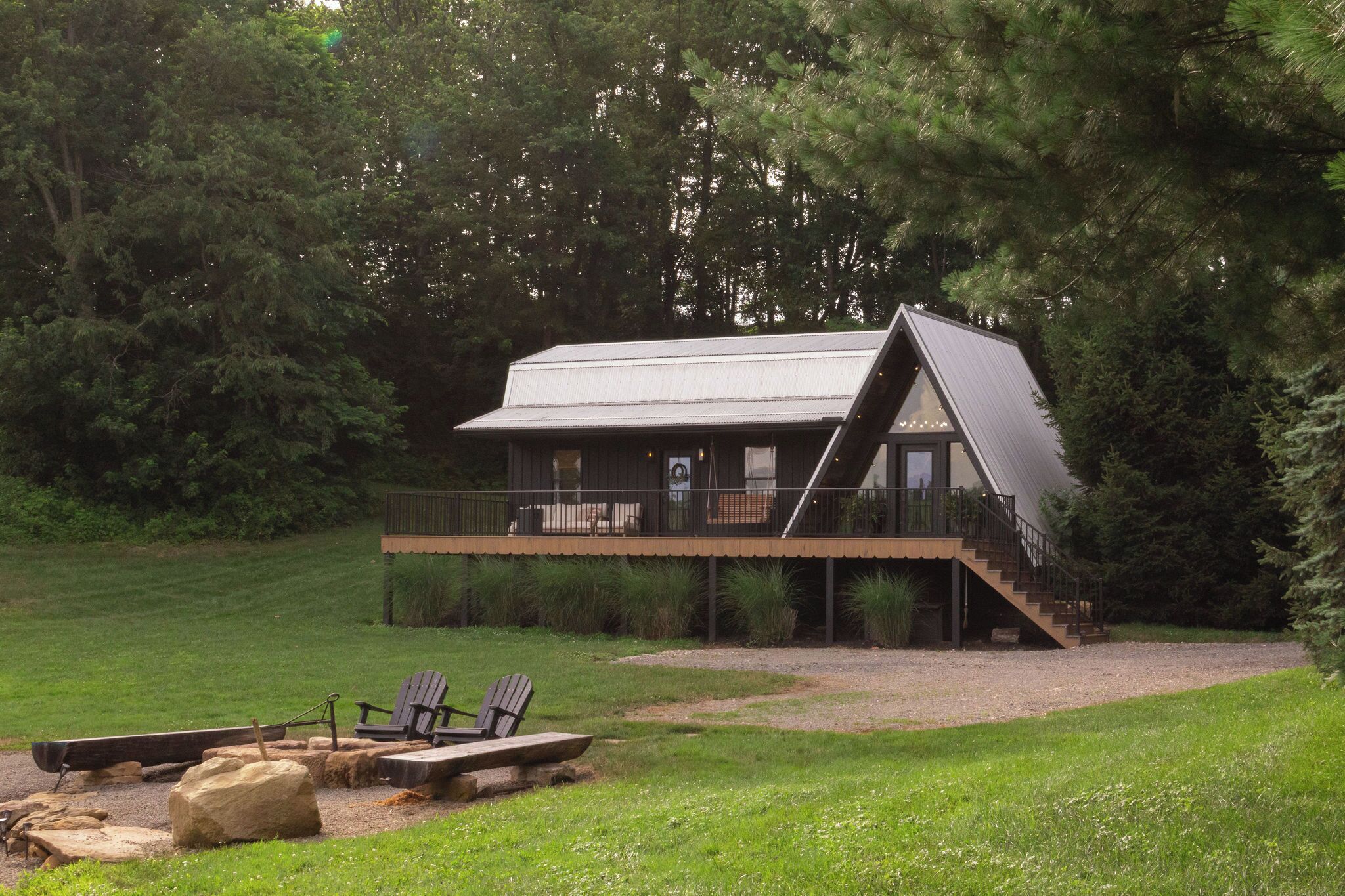 A cabin with a balcony, a deck, and a fire pit area.