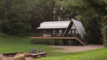 A cabin with a balcony, a deck, and a fire pit area.
