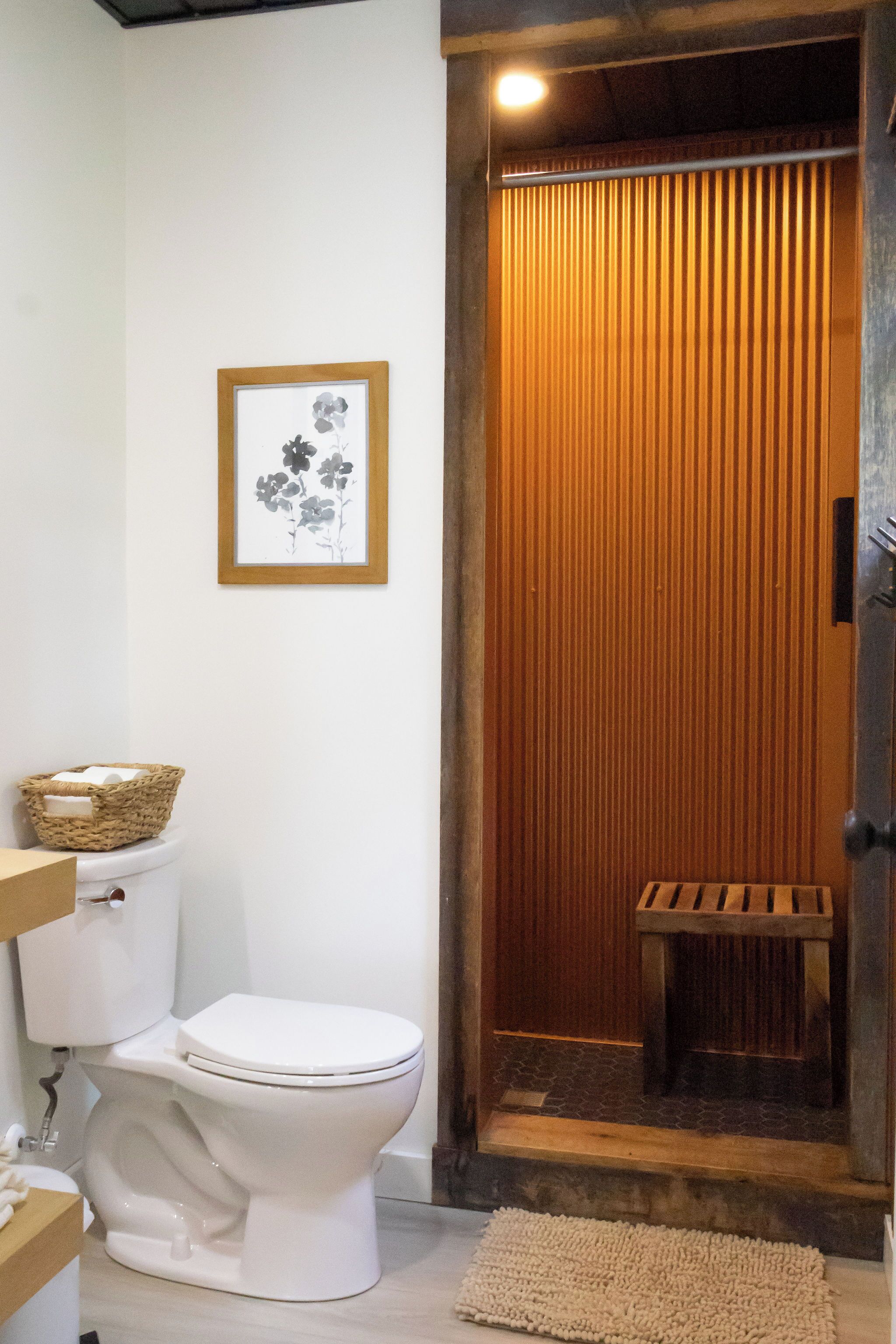 Een badkamer met een wit toilet, een houten deur en een lijst met een foto aan de muur.