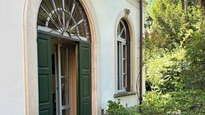 A building with a stone facade, green doors, and a small garden with potted plants. - The Lemon House Lemon House at the Lake. Elegant apartment with garden (Bellagio)