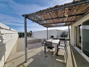 An outdoor patio with a table and chairs, a pergola, and a stone wall. - Air-Conditioned House for 4–6 Guests Near Saintes Maries de la Mer (Saintes-Maries-de-la-Mer)