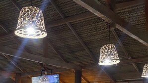 A spacious indoor dining area with wooden tables and chairs, hanging pendant lights, and large windows offering a view of the outdoors. - Amazon tucuna ecologico  (Careiro)