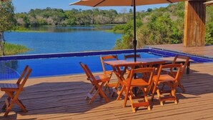 A wooden deck with a pool, lounge chairs, and umbrellas. - Amazon tucuna ecologico  (Careiro)