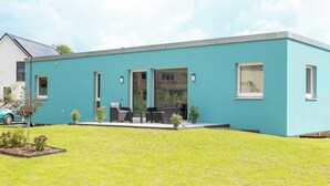 Een modern gebouw met een plat dak, grote ramen en een uitbouw met plat dak.