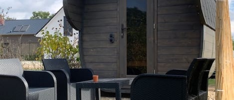 Una cabaña de madera con techo curvo, una mesa y dos sillas.