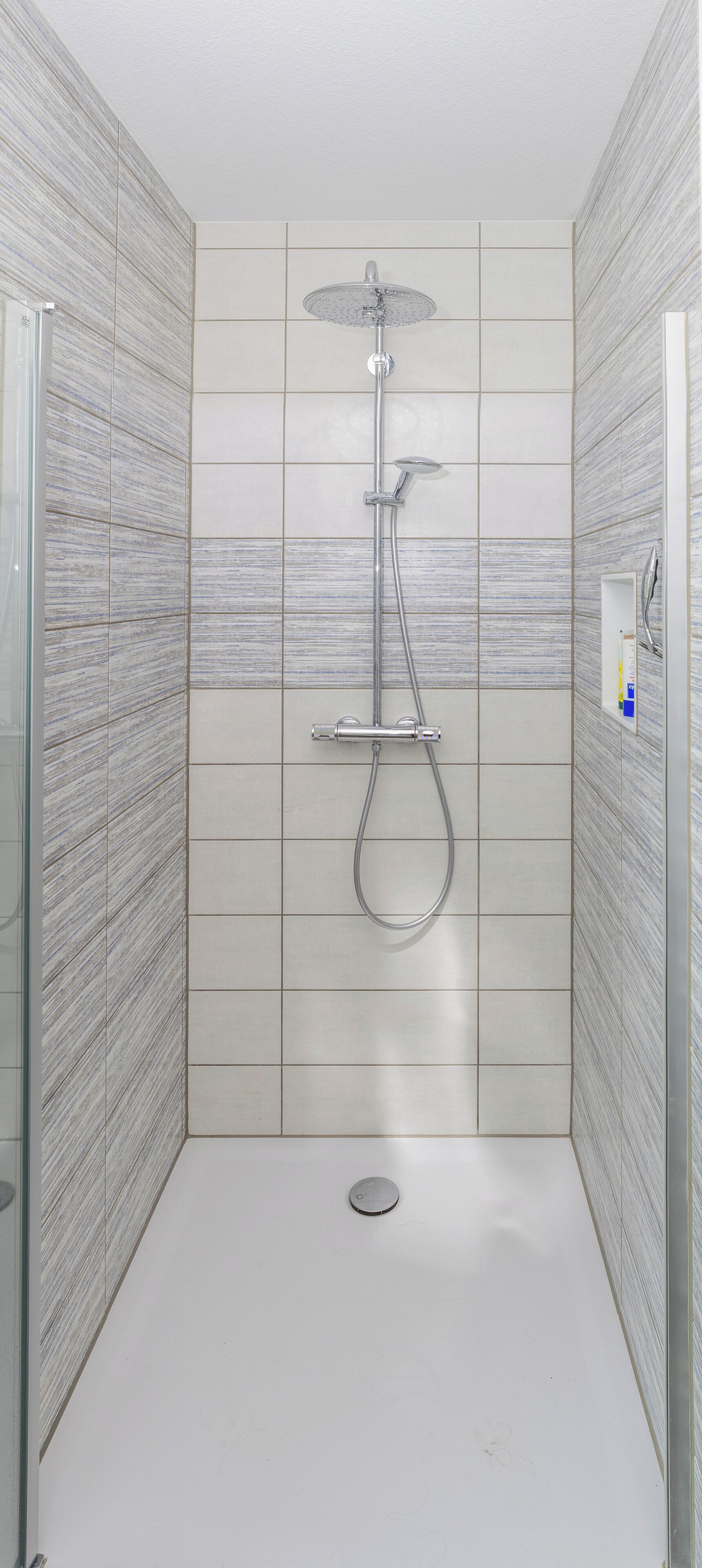 Eine Dusche mit Duschbrause und Wandarmatur.