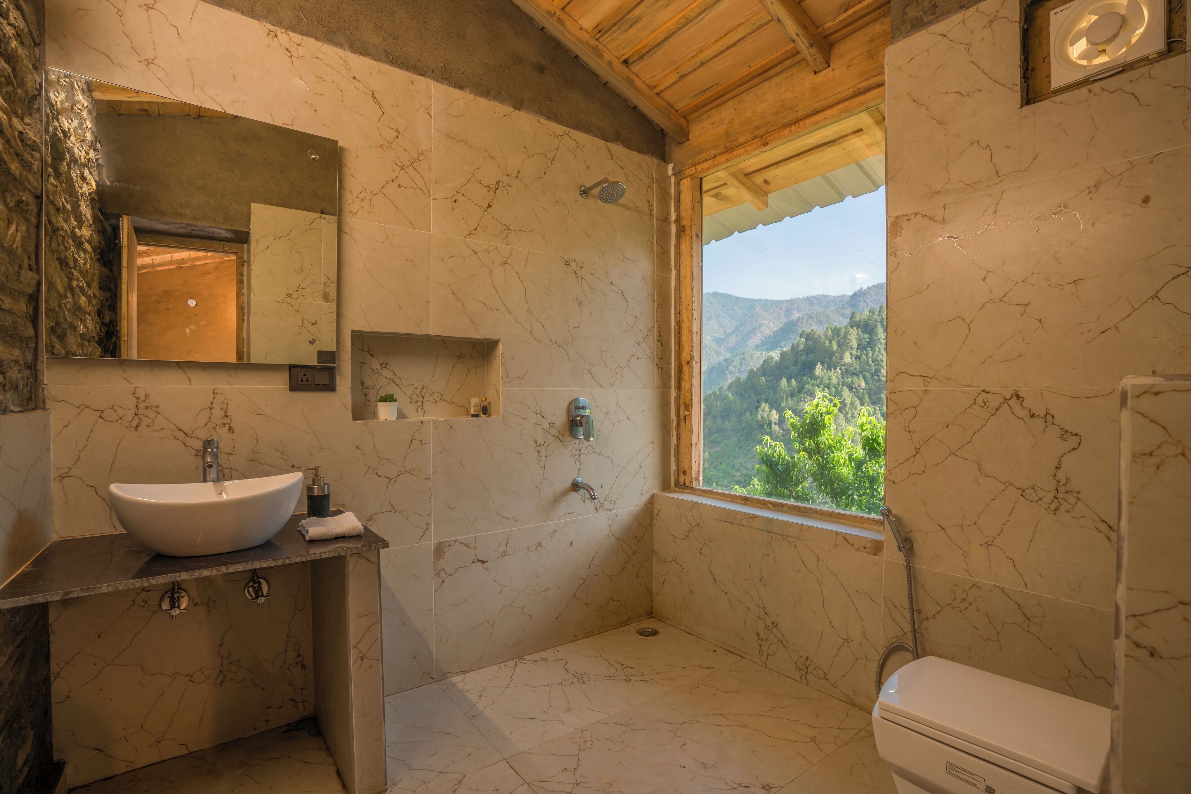A bathroom with a marble sink, a toilet, and a shower. There is a window providing a view of the outdoors.