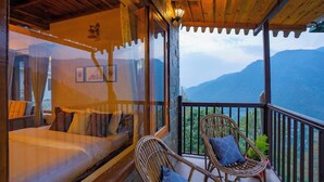 A balcony with wicker chairs and a bed with a view of mountains. - Indulge Ramgarh Nainital by PACK (Kosiyakutoli)