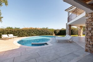 A swimming pool with lounge chairs, stone pillars, and a clear view of the surrounding landscape. - VILLA MELOGRANO - A blend of discreet elegance and total comfort, only 500 meters from Sardinia’s most stunning waters (Castiadas)