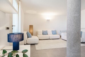 A modern living room with a white sofa, a blue lamp, and a stone pillar. - VILLA MELOGRANO - A blend of discreet elegance and total comfort, only 500 meters from Sardinia’s most stunning waters (Castiadas)