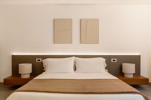 A modern bedroom with a large bed, two bedside tables with lamps, and two framed artworks on the wall. - VILLA MELOGRANO - A blend of discreet elegance and total comfort, only 500 meters from Sardinia’s most stunning waters (Castiadas)
