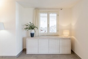 A room with a window, a bedside table with a lamp, and a potted plant. - VILLA MELOGRANO - A blend of discreet elegance and total comfort, only 500 meters from Sardinia’s most stunning waters (Castiadas)