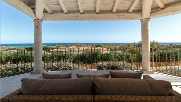 Un espacio de estar techado al aire libre con vista al mar y a un viñedo.