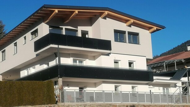 Een gebouw met meerdere verdiepingen, balkons, een plat dak en een stenen basis.