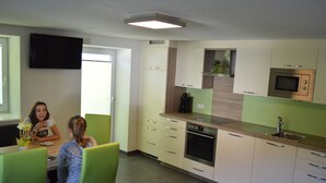 Een moderne keuken met een ingebouwde oven, magnetron en koffiezetapparaat. Twee personen zitten aan een tafel met stoelen.