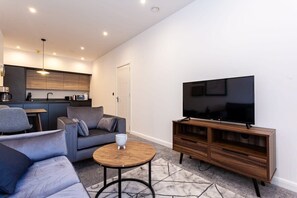 A modern living room with a sofa, coffee table, TV, and wooden cabinet.