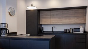 A modern kitchen with dark cabinetry, a built-in microwave, and a coffee maker on the counter. - Chic 1BR Bolton Apt near Manchester Rail (Bolton)
