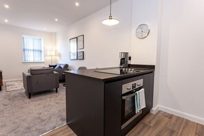 A modern kitchen with a central island, built-in oven, and a coffee maker.