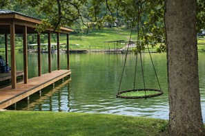 A wooden dock extending into a calm lake, a swing hanging from a tree, and a gazebo with a roof. - Cozy 1-bedroom Shop House on beautiful Lake Hamilton in Hot Springs (Hot Springs)