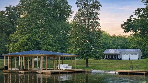Una propiedad junto al lago con un pabellón de madera, un muelle y una casa con garaje.