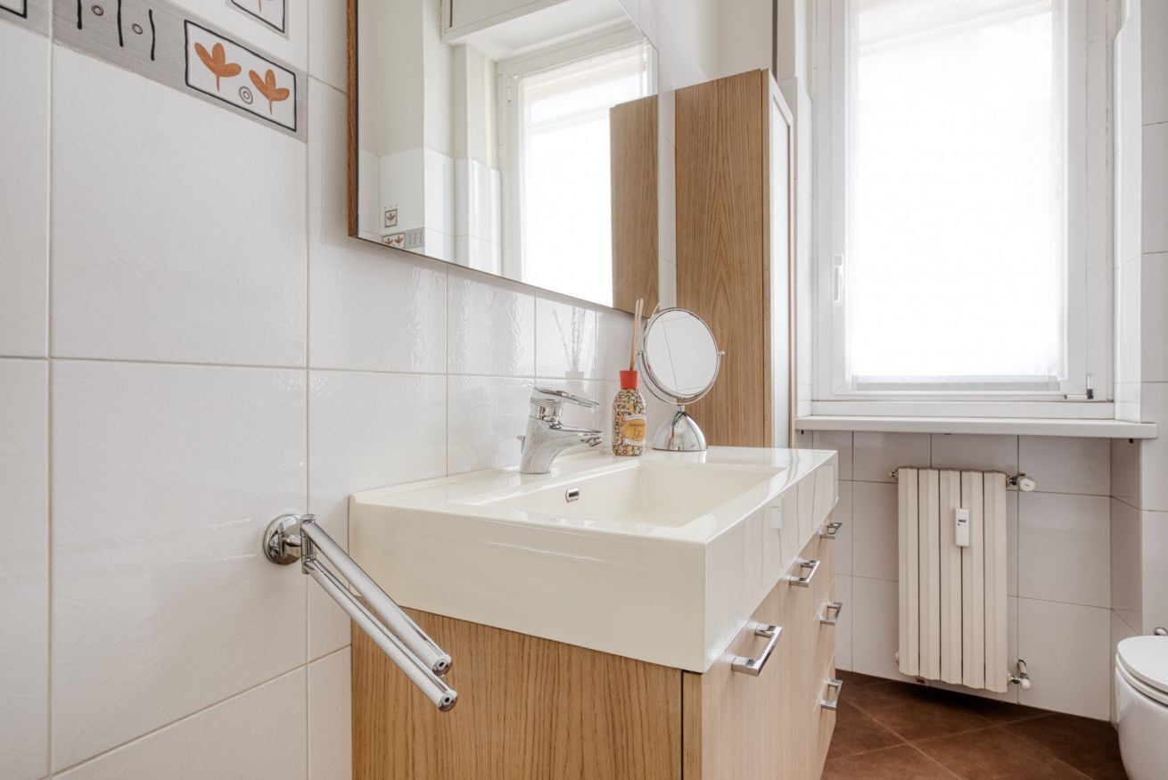 Ein modernes Badezimmer mit Waschbecken, Spiegel und Holzschrank.