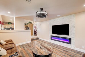 A modern living room with a flat-screen TV mounted on a stone wall, a wooden coffee table, and a leather sofa. - Luxury,5 Bed rooms,private pool /Spa Near Strip &Airport,15 %/25% Special offer! (Las Vegas)
