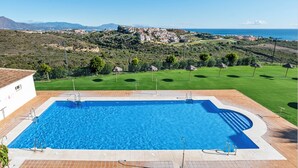 En swimmingpool med utsikt över en kuststad och berg i bakgrunden.
