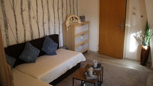 A bedroom with a bed, a wooden dresser, a nightstand, and a potted plant. - Vacation cottage Ewald (Enkirch)