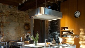 Een moderne keuken met een centraal eiland, roestvrijstalen apparatuur en een vloer met een patroon.