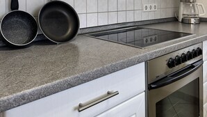 A kitchen with white cabinets, a stainless steel range, a double oven, and a coffee maker. - Fewo Eichhölzle 1, 90 sqm, 2 Bedrooms, Max. 4 Guests (Münsingen)