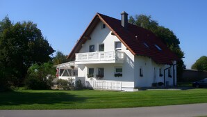 A two-story house with a balcony, a red roof, and a white exterior. - Fewo Eichhölzle 1, 90 sqm, 2 Bedrooms, Max. 4 Guests (Münsingen)