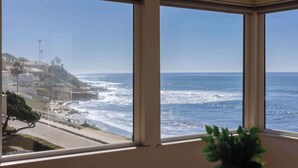 A room with large windows overlooking a coastal view. - Serene Escape at Windansea: Oceanview 2-Bedroom (San Diego)