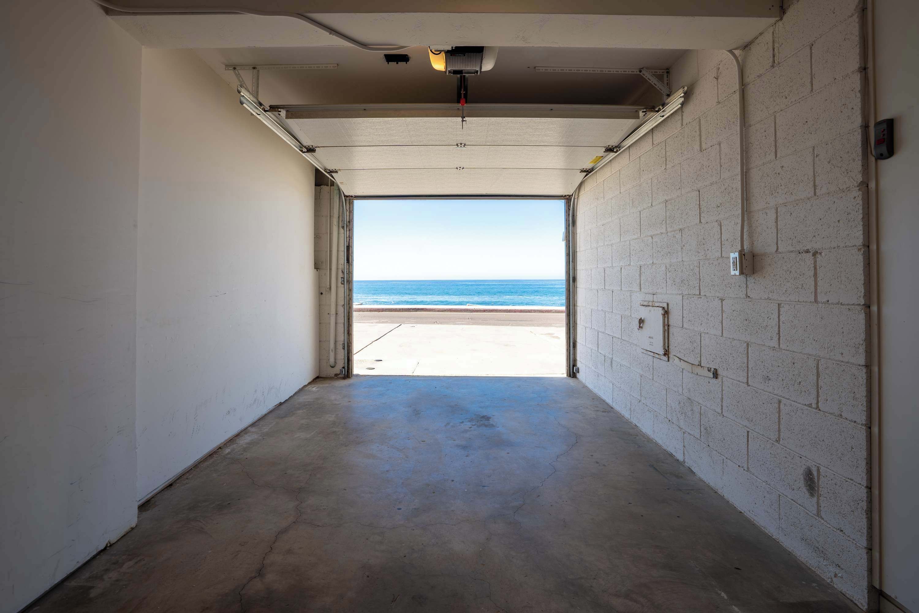 A hallway leading to a beach view with a concrete floor and brick walls.