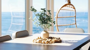 A dining area with a table, chairs, a hanging chair, and a view of the ocean. - Beachfront Bliss: Oceanview Haven at Windansea (San Diego)