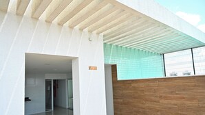 Un edificio moderno con fachada blanca, pared de madera y suelo de baldosas.