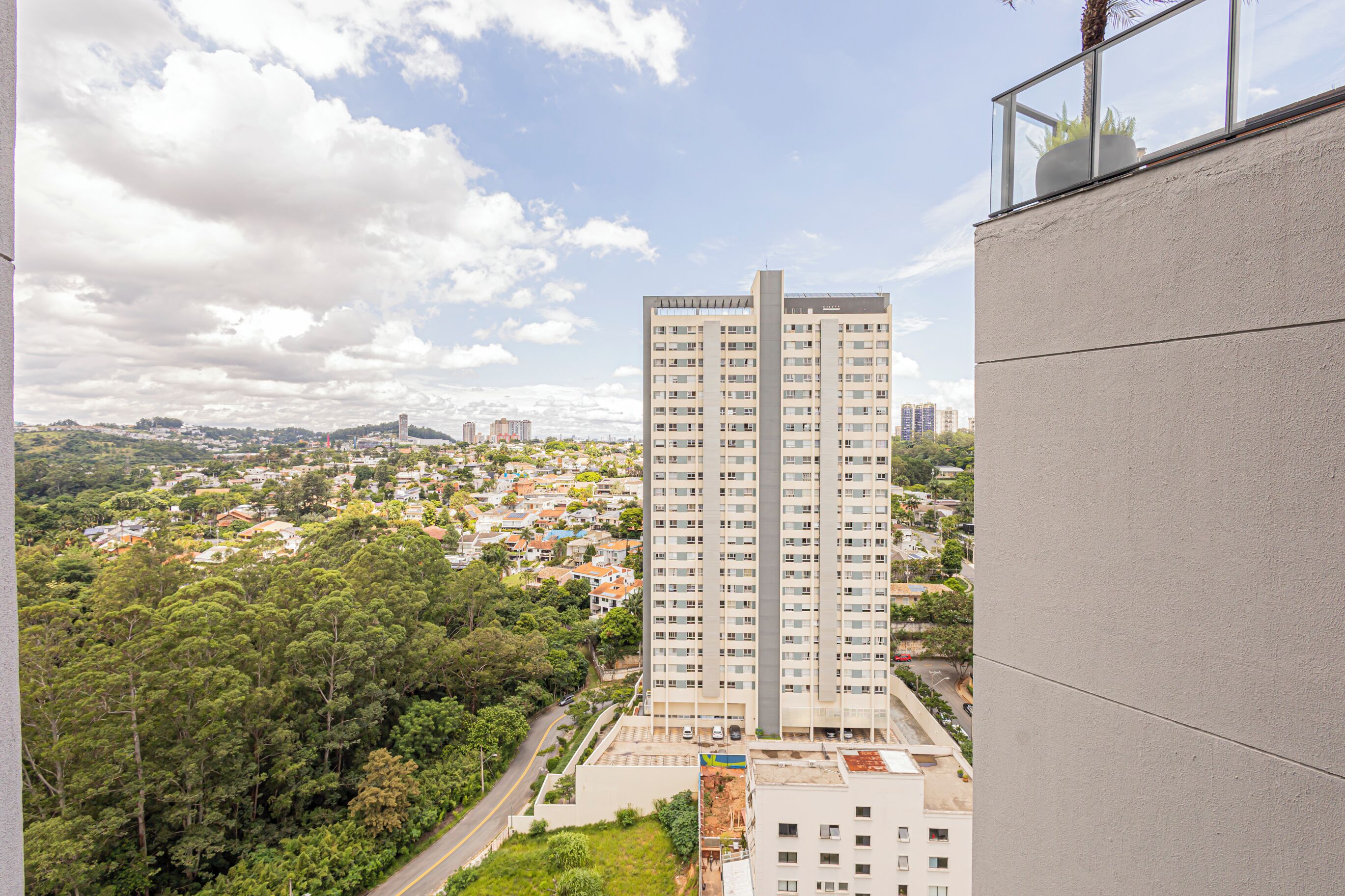 Ein Hochhaus mit mehreren Stockwerken, umgeben von Grünflächen und anderen Wohnhäusern.