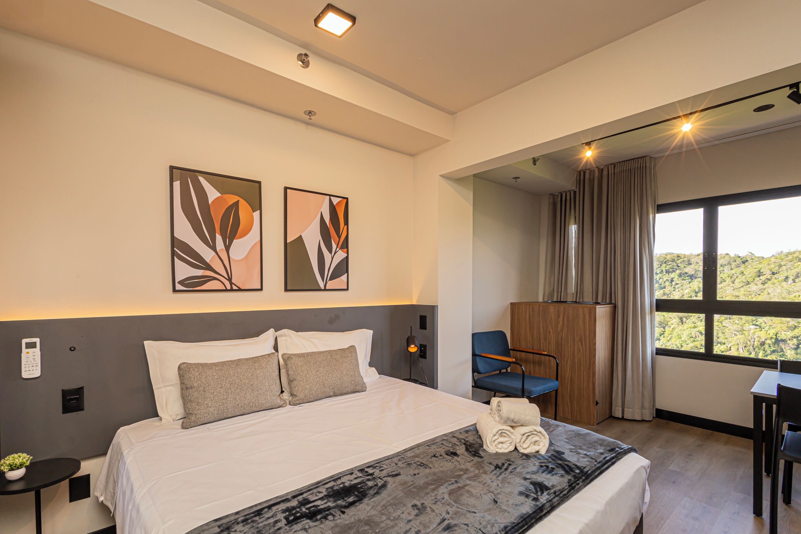 Un hotel moderno con una cama grande, un escritorio, una silla y vistas al exterior.