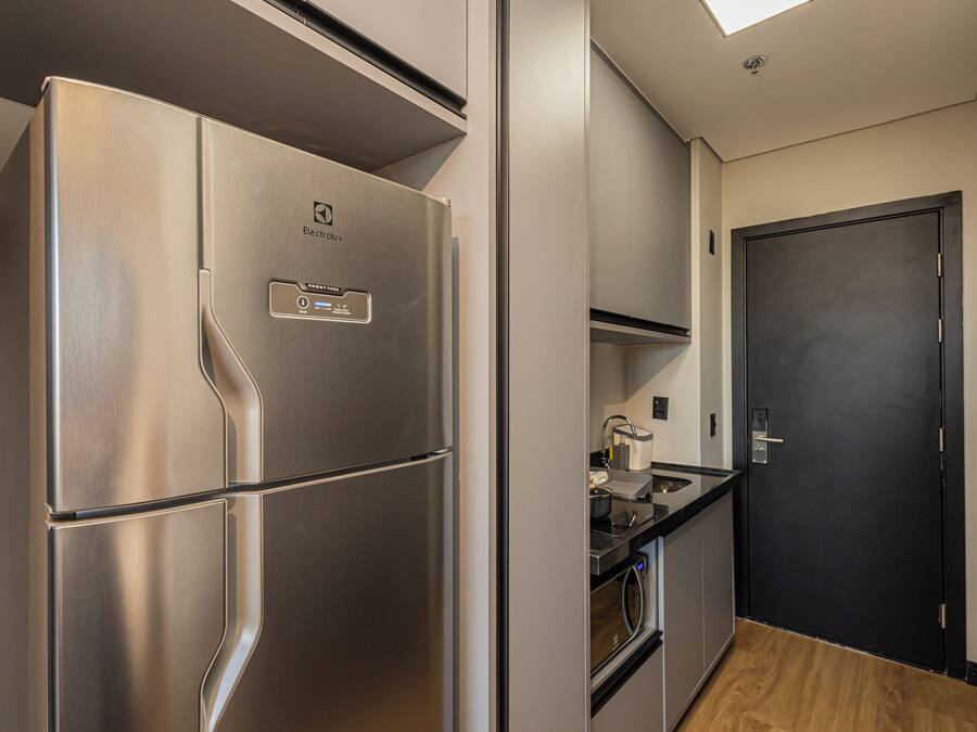 Una cocina moderna con un refrigerador de acero inoxidable, una puerta negra y piso de madera.