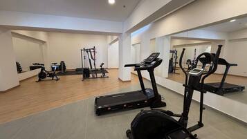 Un gimnasio con cintas de correr, elípticas y equipo de levantamiento de pesas.