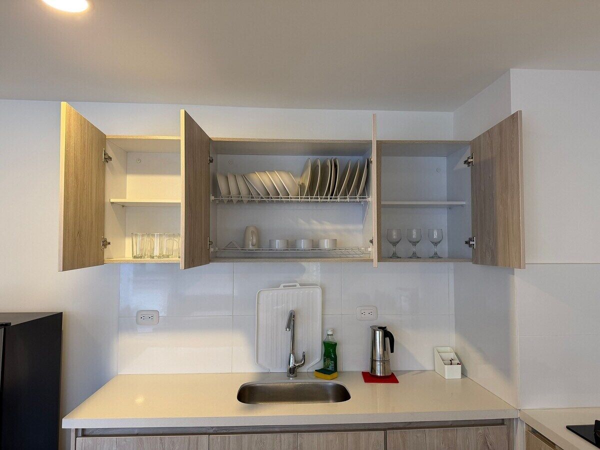 A kitchen with a built-in sink, wooden cabinets, and a dish rack above the counter.