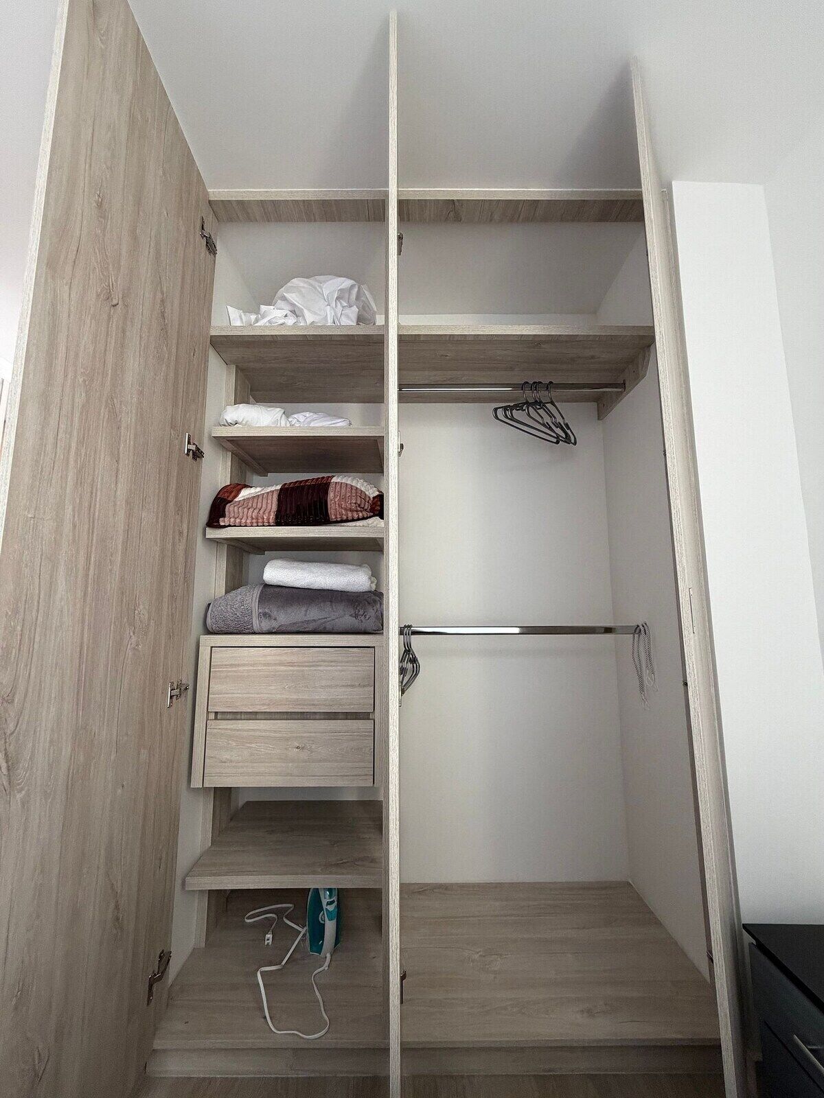 Un vestidor amplio con estantes abiertos, una barra para colgar ropa y un conjunto de cajones.