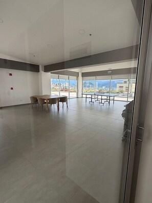 A spacious room with a large table and chairs, a ping pong table, and large windows offering a view of the cityscape. - Comfortable & Stylish – Premium Area (Manizales)