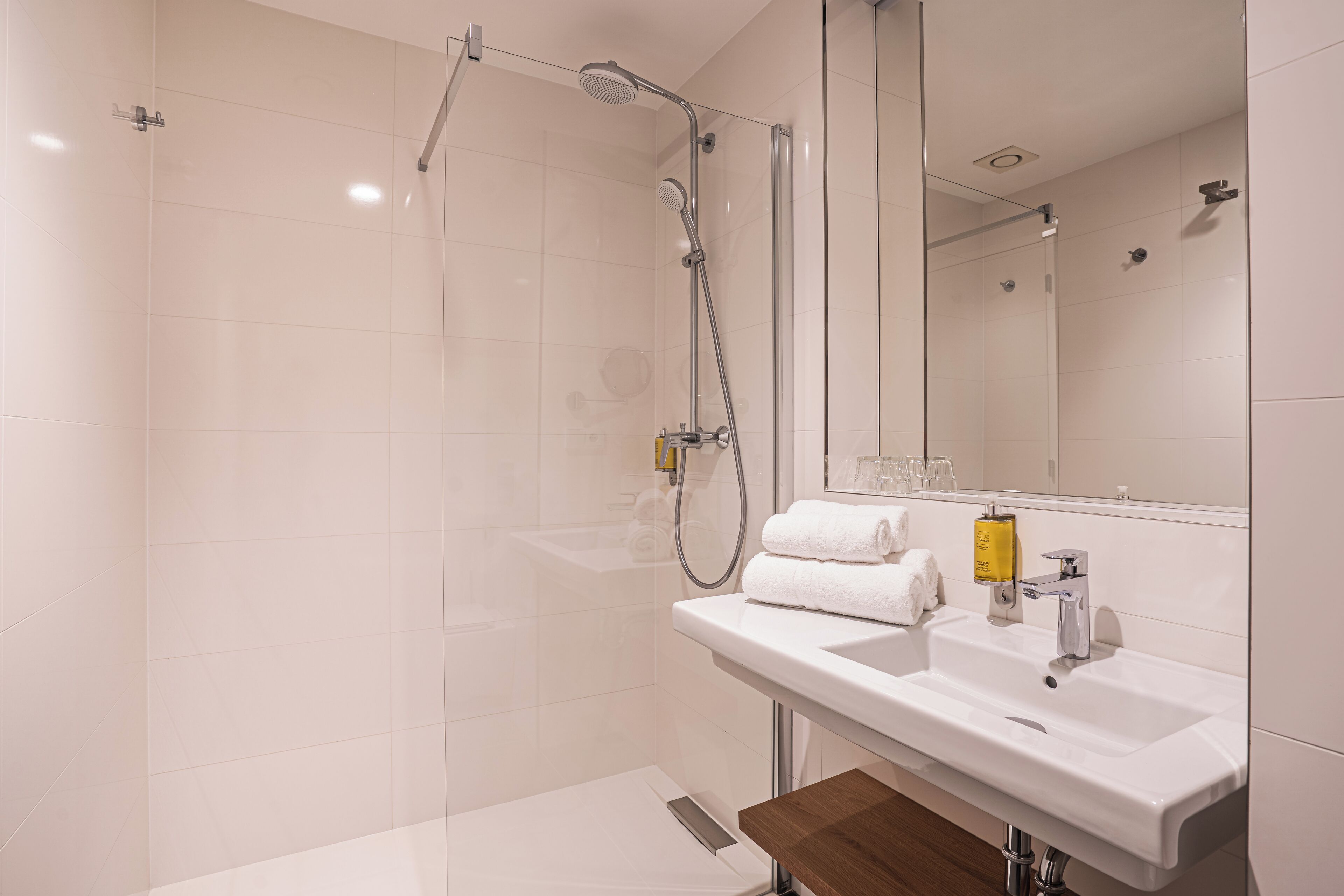 A modern bathroom with a shower, sink, and mirror.