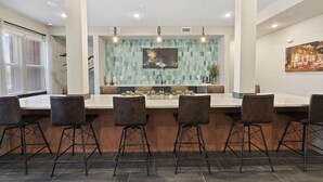 A modern kitchen with a central island, bar stools, and a backsplash with a geometric pattern. - Landing | Modern 1BD, Gym, Pool (Nashville)