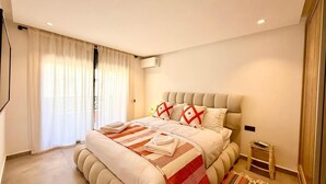 Une chambre à coucher moderne avec un grand lit, une tête de lit et une petite table de chevet.