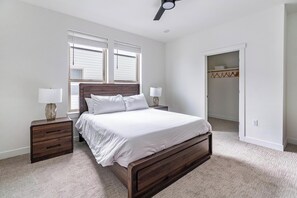 Ein Schlafzimmer mit einem hölzernen Bett, zwei Nachttischen, einem Schrank mit geometrischem Muster und einem Deckenventilator.