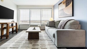 A modern living room with a sofa, coffee table, and a TV. - Landing | Stylish 1BD, Yoga Studio, Game Room (Hartford)